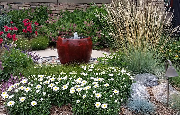 Bubbling pot water feature with colorful plantings.