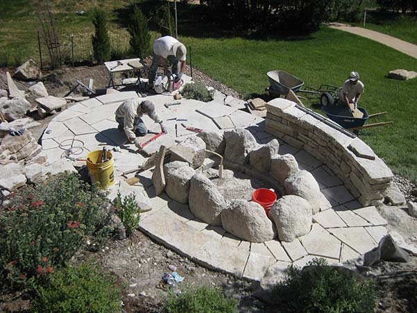 Stone patio with fire pit under construction.