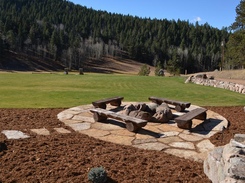 Siloam stone patio with boulder fire pit in the forest.