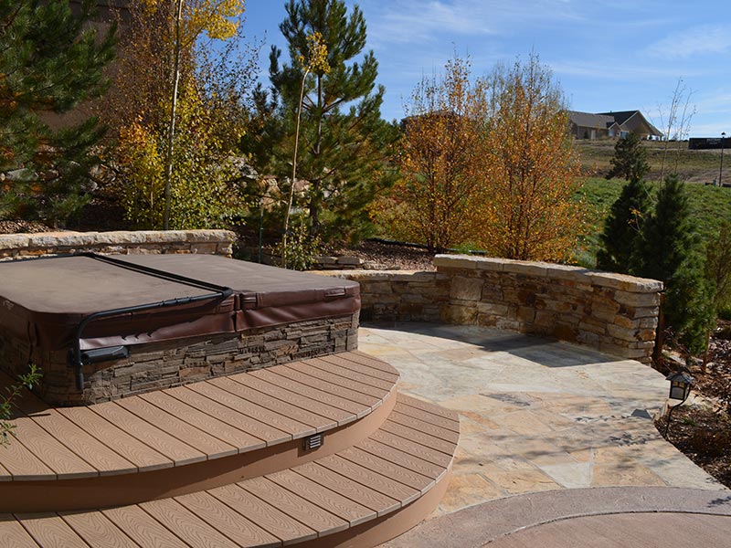 Backyard patio with flagstone finish, natural stone walls, and hot tub.