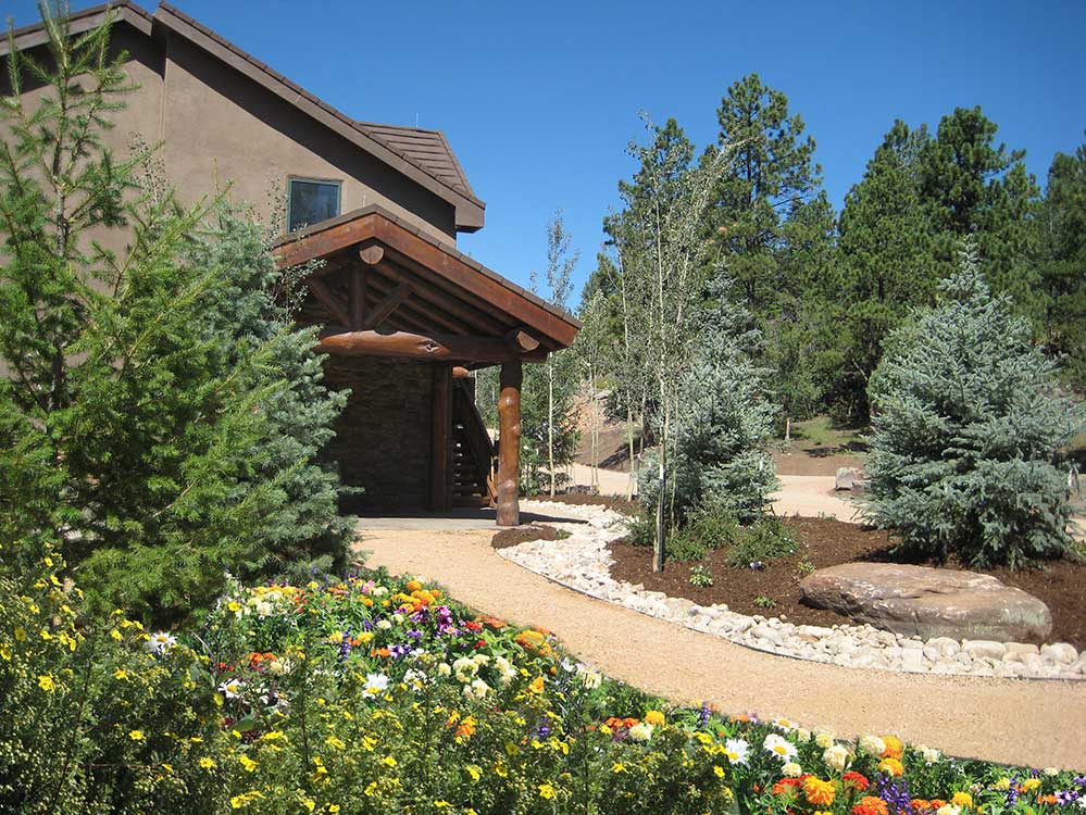 This rustic landscape features a large decorative boulder and cobble dry creek bed that accent the planting areas beautifully.